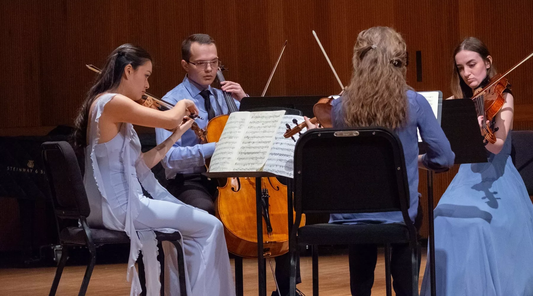 Four students playing string instruments