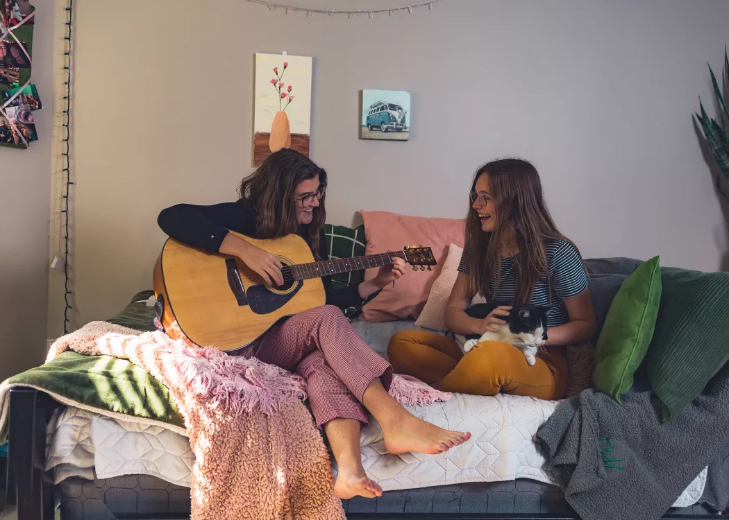 Music  therapy majors Caroline Rushing and Mackenzie Aldridge entertain each other in the Rose Anna Hughes Home room they share with cat Louie.