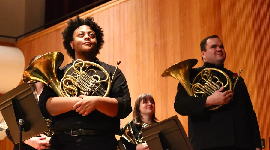 Students standing with their french horns