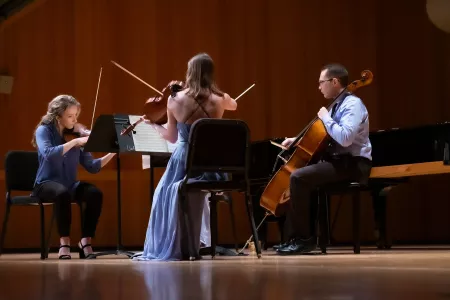 Three students playing string instruments